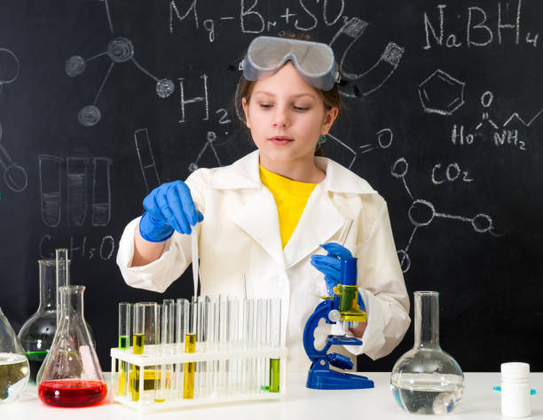 istock schoolgirl in white gown doing experiments with liquids 1410097391