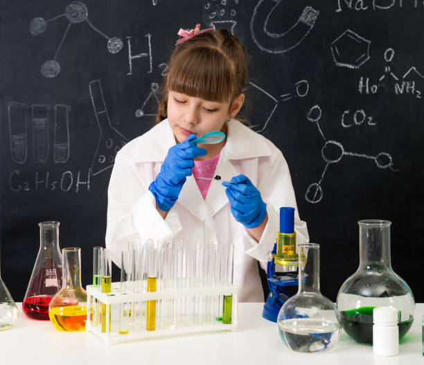 istock little schoolgirl looking through magnifier on reagents 1410097407