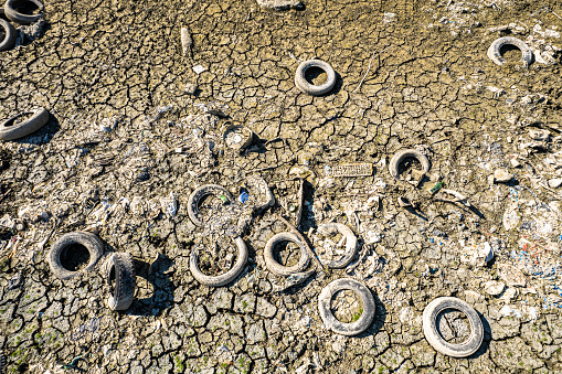 Old tire illegally abandoned in Po river visible due to drought. Carmagnola, Italy - July 2022