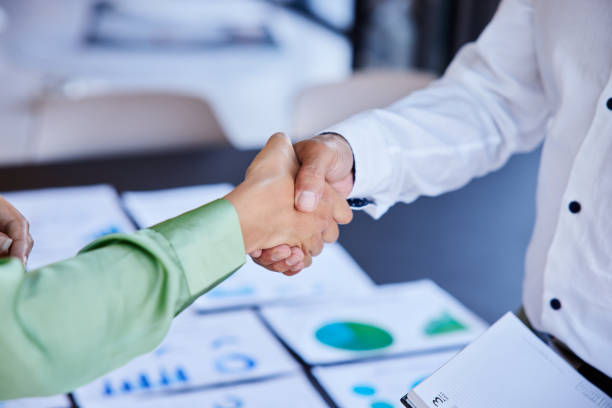 istock Businesspeople shaking hands together after analyzing paperwork in an office 1410098378