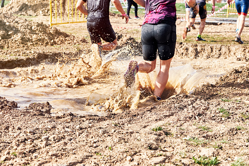 Group of participants in an obstacle course race running across a pool of water. Spartan race. Concept of hardness and effort