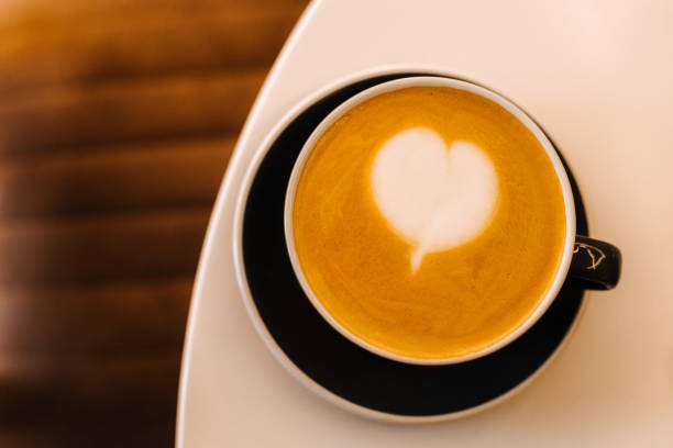 istock Black cup of cappuccino on saucer with latte art on white table background. 1410098849