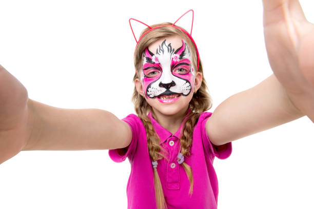 istock cute little girl with painted mask on face making selfie 1410098976
