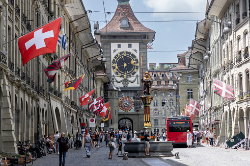 Bern Switzerland , 22 June 2022 : Tourists in old Kramgasse street with Samsonbrunnen or Samson fountain and Zytglogge clock tower in Bern old town Switzerland