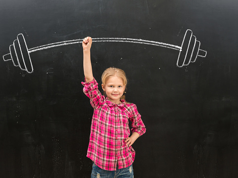 cute little girl rising up drawn on the blackboard barbell with one hand