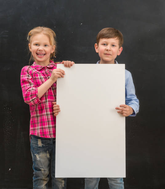 istock two smiling schoolchildren with blank sheet of paper 1410100302