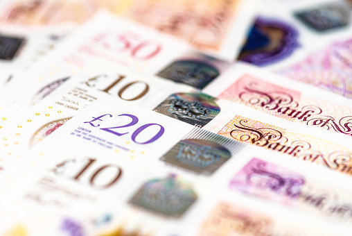 Macro image of several GBP notes issued by the Bank of England, including £10, £20 and £50 banknotes.