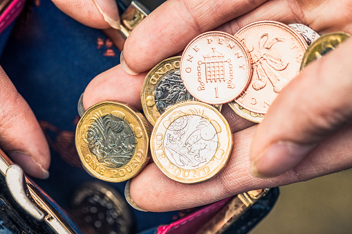 Close-up of a woman's hand holding one pound coins and other change from her purse.