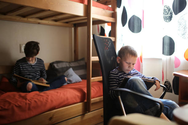 istock Brothers with book and tablet, family relations 1410105544
