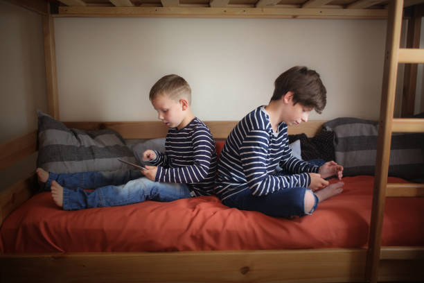 istock Brothers play gadgets on bed,relationships 1410105551