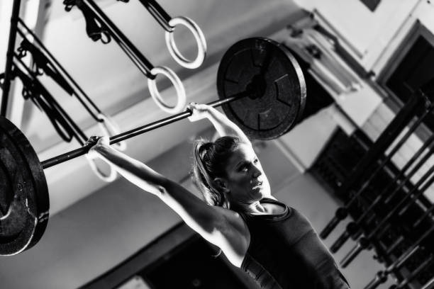 istock Cross training. Female athlete lifting heavy barbells 1410105637