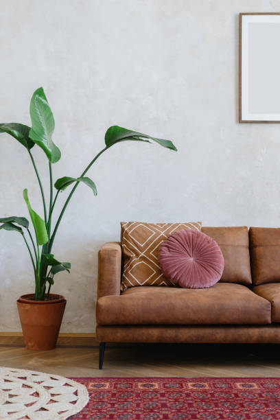 istock Brown sofa, pillows, picture frame on wall and potted green plant 1410106232