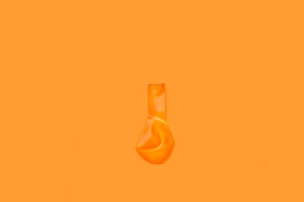 istock A deflated orange pink balloon on an orange background 1410106465