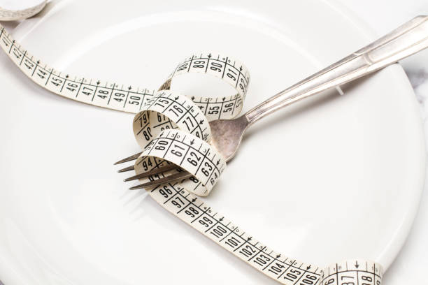 istock A measuring tape and a fork on a white plate on a marble background 1410106479
