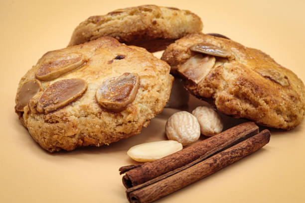 biscoitos de amêndoas doces caseiros (amaretti) isolados em laranja com três amêndoas e dois paus de canela - bakery baked biscuit sweet food - fotografias e filmes do acervo