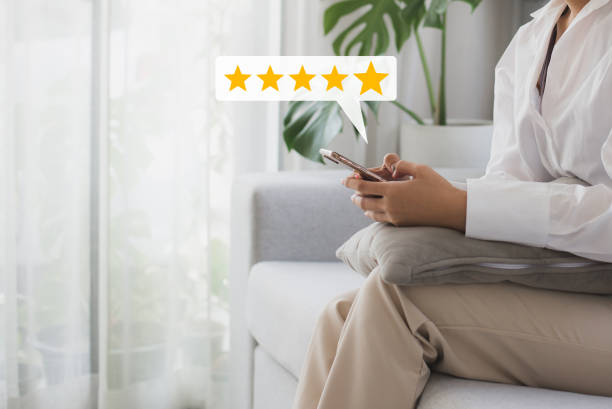 Woman customer hand pressing on smartphone screen with choose five star rating feedback icon and press level excellent rank for giving best score point to review the customer service. stock photo