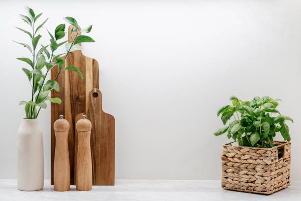 Wooden cutting board, kitchenware and plant in basket Wooden cutting board, kitchenware and plant in basket on table in kitchen. Home comfort and decor. Eco-friendly kitchenware. Household equipment salt and pepper shaker stock pictures, royalty-free photos & images