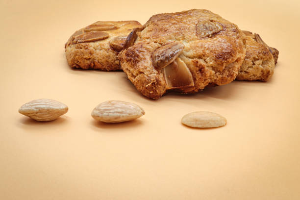 biscoitos de amêndoas doces caseiros (amaretti) isolados em laranja com três amêndoas - bakery baked biscuit sweet food - fotografias e filmes do acervo