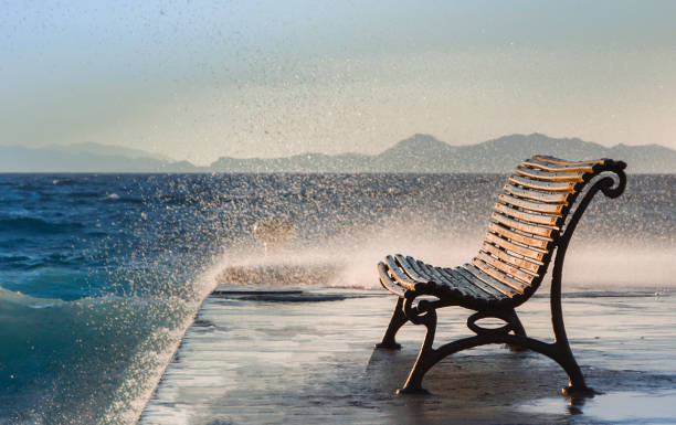 Bench for rest among the sea splashes at sunset. Summer vacation or vacation at sea.