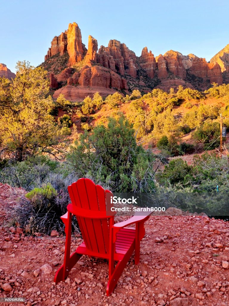Empty Adirondack Chair with a Desert Mountain View Empty red adirondack chair overlooking the beautiful desert mountains of Sedona, Arizona, USA at sunset. Mountain Stock Photo