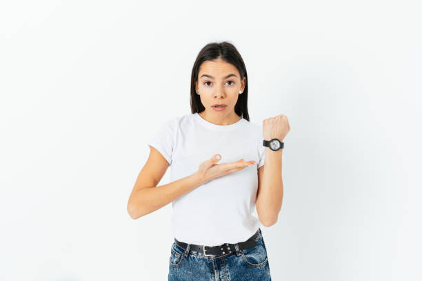 istock Late again, displeased young woman points to the clock 1410109385