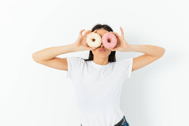 istock Portrait funny young woman posing with two donuts as glasses 1410109423