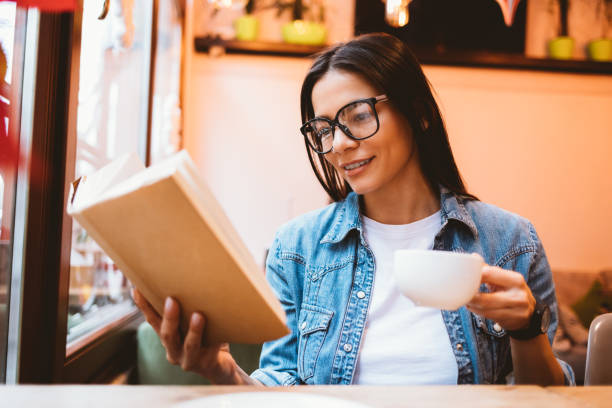 istock Young woman wearing glasses reading a book 1410109517
