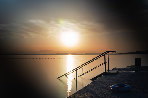 Railing of a bathing ladder against the light of the setting sun in Croatia.