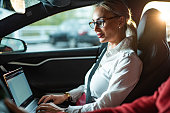 Businesswoman using laptop while traveling by car