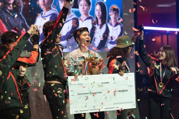 Asian Esports team holding  trophy mock up cheque cheering winning  grand final videogame on stage. Videogame Championship Arena. Cyber Games Tournament Event