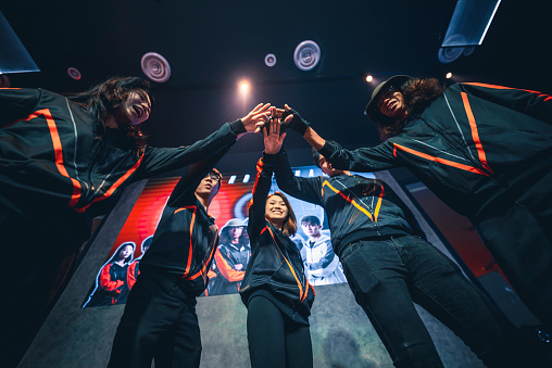 Asian Chinese Esports grand final team standing in front of stage with projector screen looking at camera with confidence look