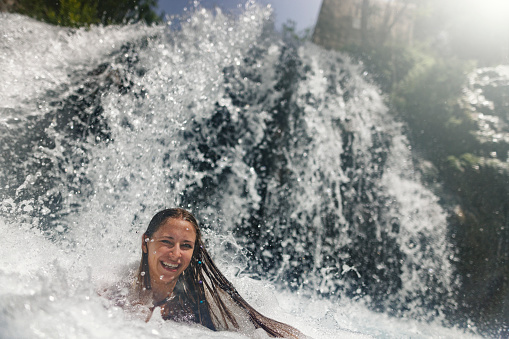 Teenager girl hiking in Valencia province, Spain. She is taking a bath in the mountain river, near a waterfall.\nSunny summer day.\nCanon R5