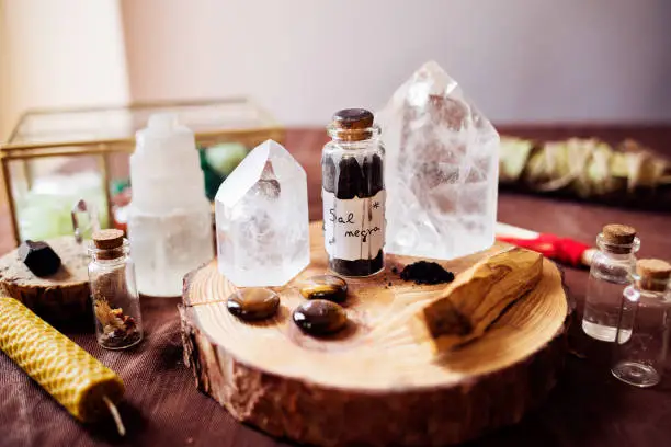 Witch altar for protection rituals against bad energies. There is a glass jar with black salt and three tiger's eye stones, palo santo and several quartz stones for energy cleaning. Translation: Black Salt