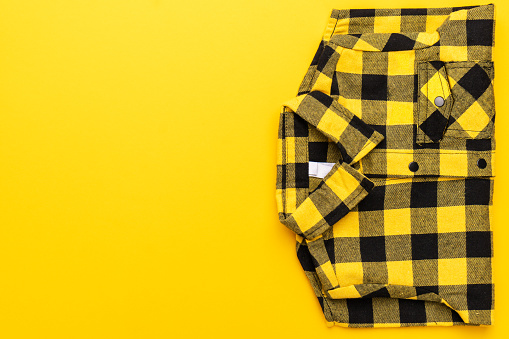 yellow and black checkered shirt on the yellow background. top view of yellow shirt with copy space.
