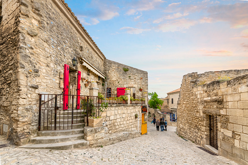 A picturesque stone street and alley of shops and cafes in the medieval village of Les Baux-de-Provence in the Alpilles mountains of Southern France.
