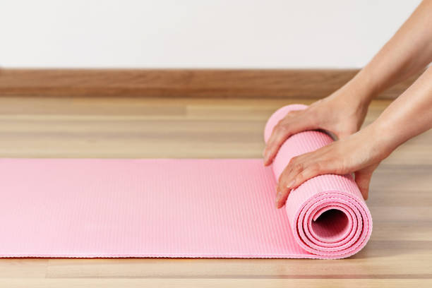 istock Woman rolling exercise mat in living room. 1410117368