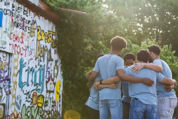 Photo of Coworkers stand in a circle near the graffiti wall