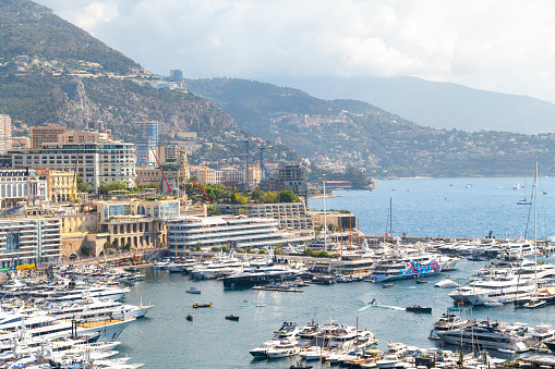 View from the Rock of Monaco of the Grand Prix race track, city skyline, mountains and harbor filled with luxury yachts in Monte Carlo, Monaco.