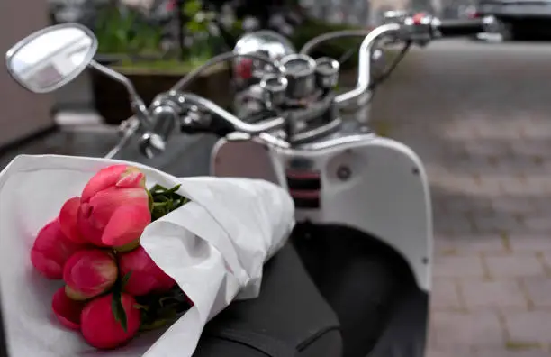 Photo of Beautiful peonies flower wrapped in white paper delivered with white moped.