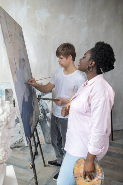 istock A boy standing near the easel and drawing with great involvement 1410123080
