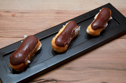 Chocolate cream eclairs on a black plate