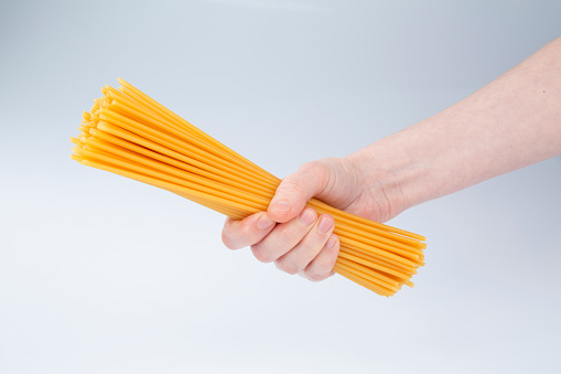 Spaghetti pasta and women hand on white background