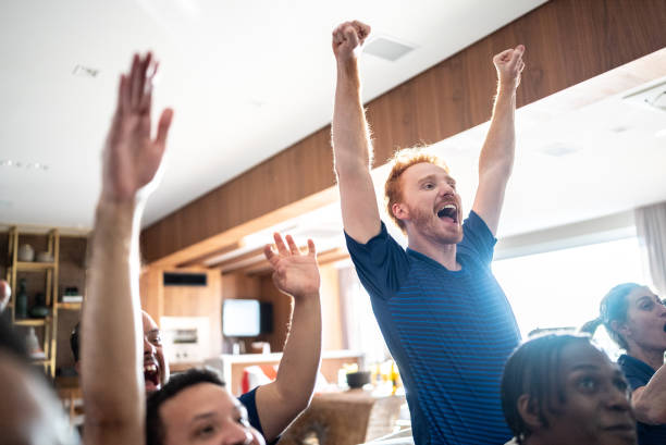 Sports fans celebrating while watching a match at home