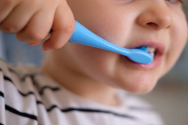Baby brushing teeth Baby brushing teeth with blue toothbrush pediatric dentistry stock pictures, royalty-free photos & images