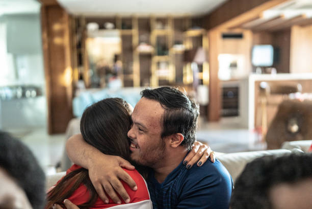istock Friends embracing while watching sports match at home - including man with special needs 1410130404