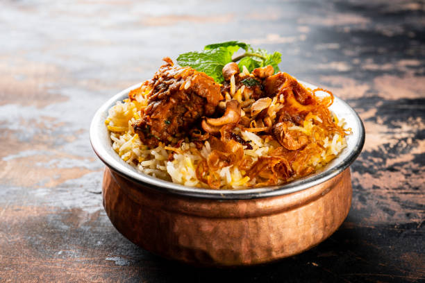 Mutton Biryani served in a golden dish isolated on dark background side view indian food stock photo