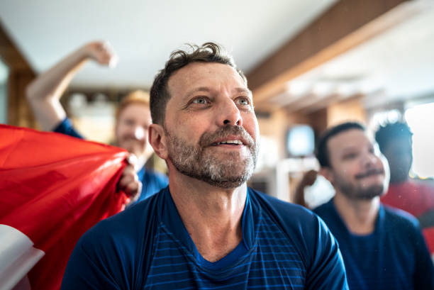 mature man watching soccer team playing a match at home with friends - fan television football watching tv imagens e fotografias de stock