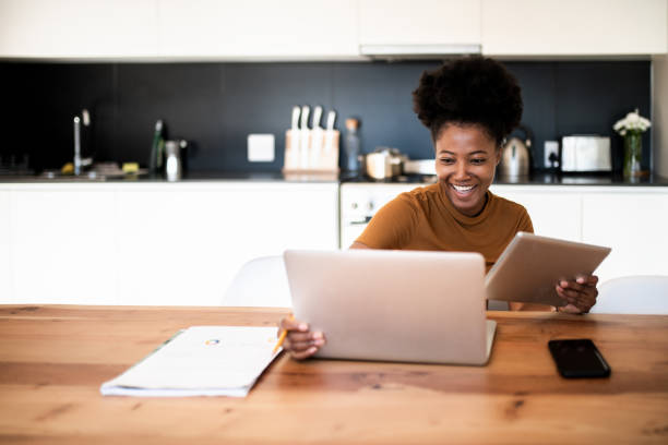 istock Young woman sitting at the kitchen table and talking on a videocall 1410132308