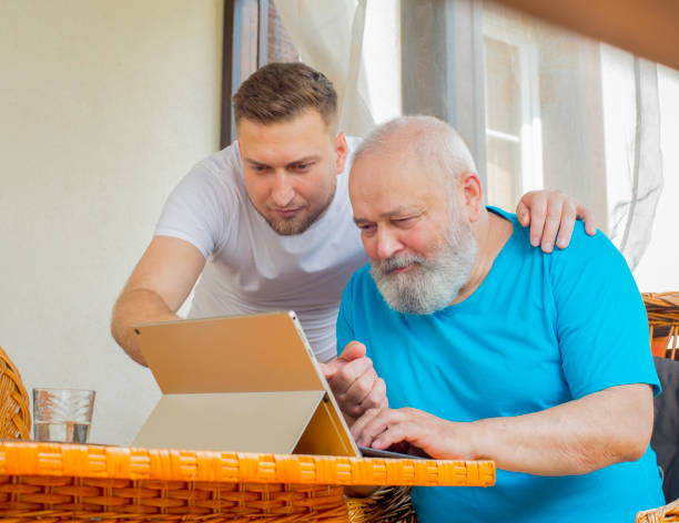 息子と父親はタブレットのラップトップを使用しています - retirement grandfather senior adult child ストックフォトと画像