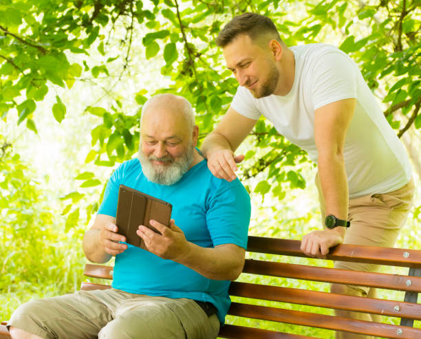 息子と父親はタブレットのラップトップを使用しています - retirement grandfather senior adult child ストックフォトと画像